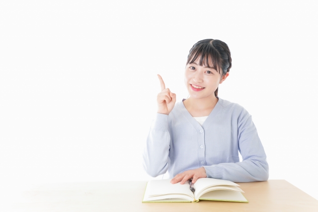 勉強をしながら指を指す若い女子学生の画像