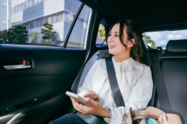 スマホを見る車の後部座席の女性