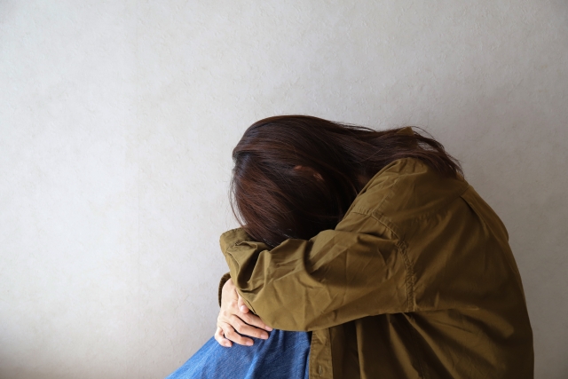 膝を抱えて座り込む女性